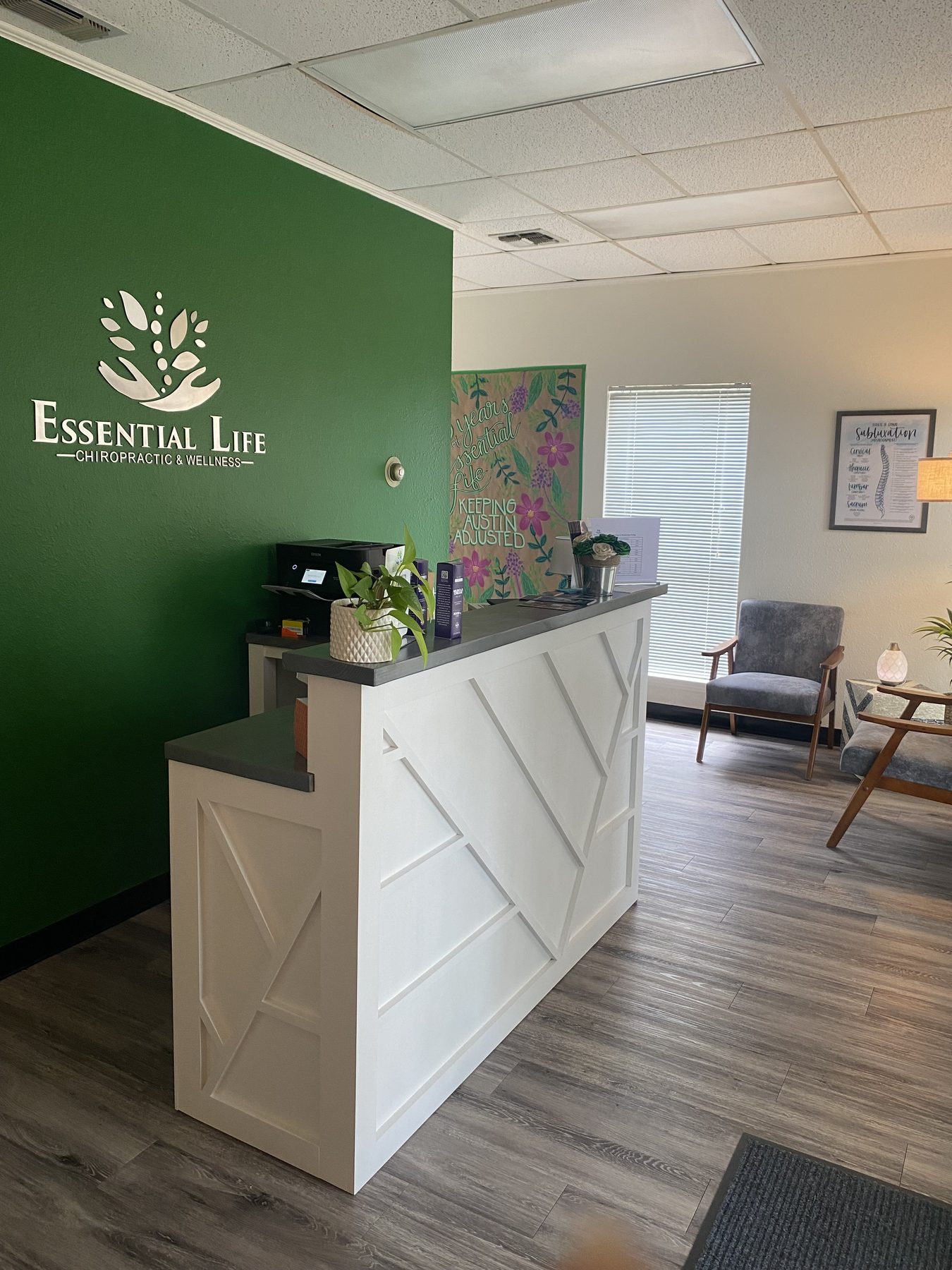 The Essential Life logo wall and front desk in the clinic's reception area