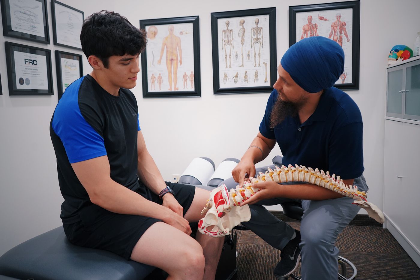 A chiropractor reviewing a spine model with a patient during a consultation