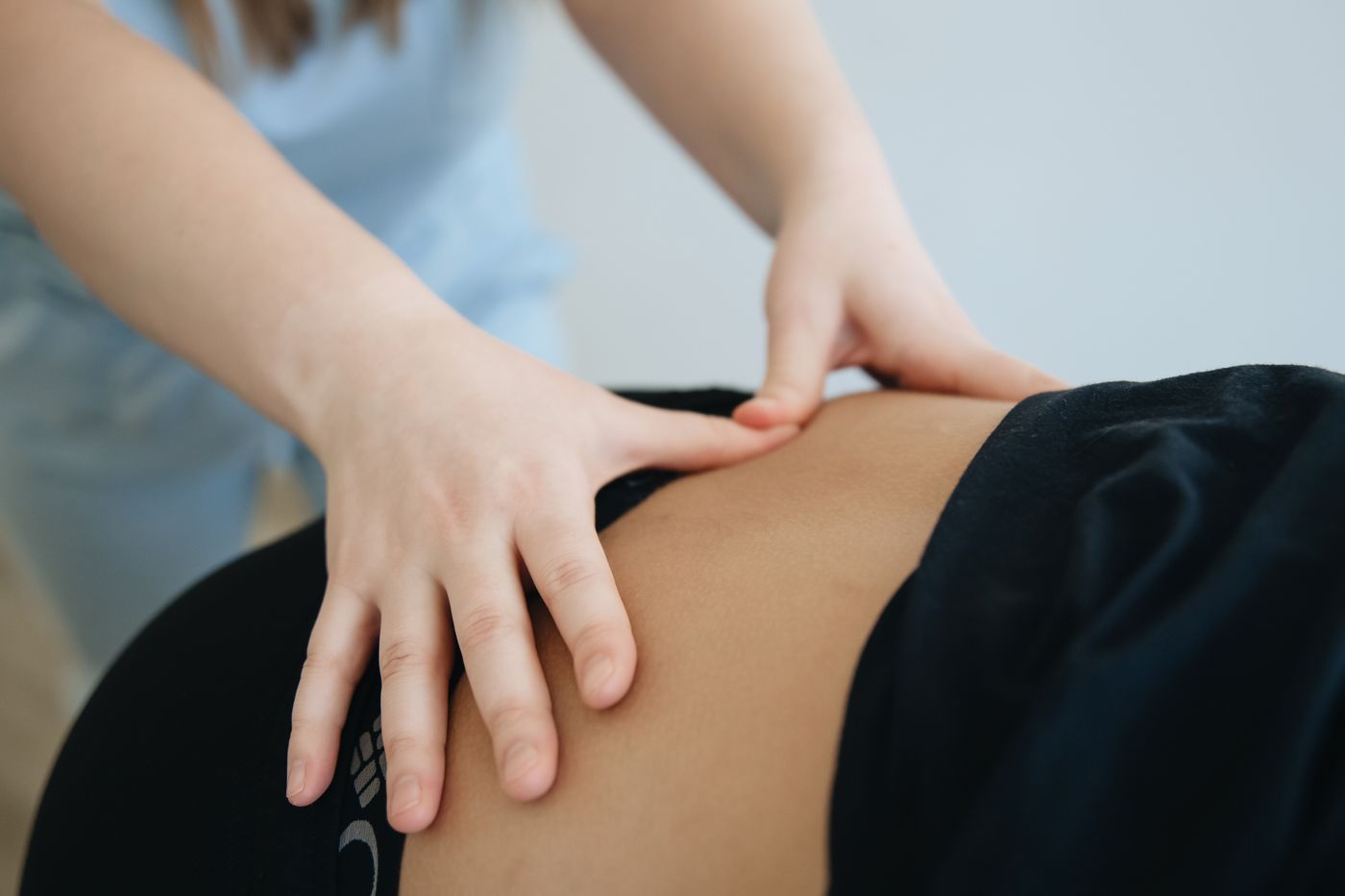 A practitioner working along a patient's lower back
