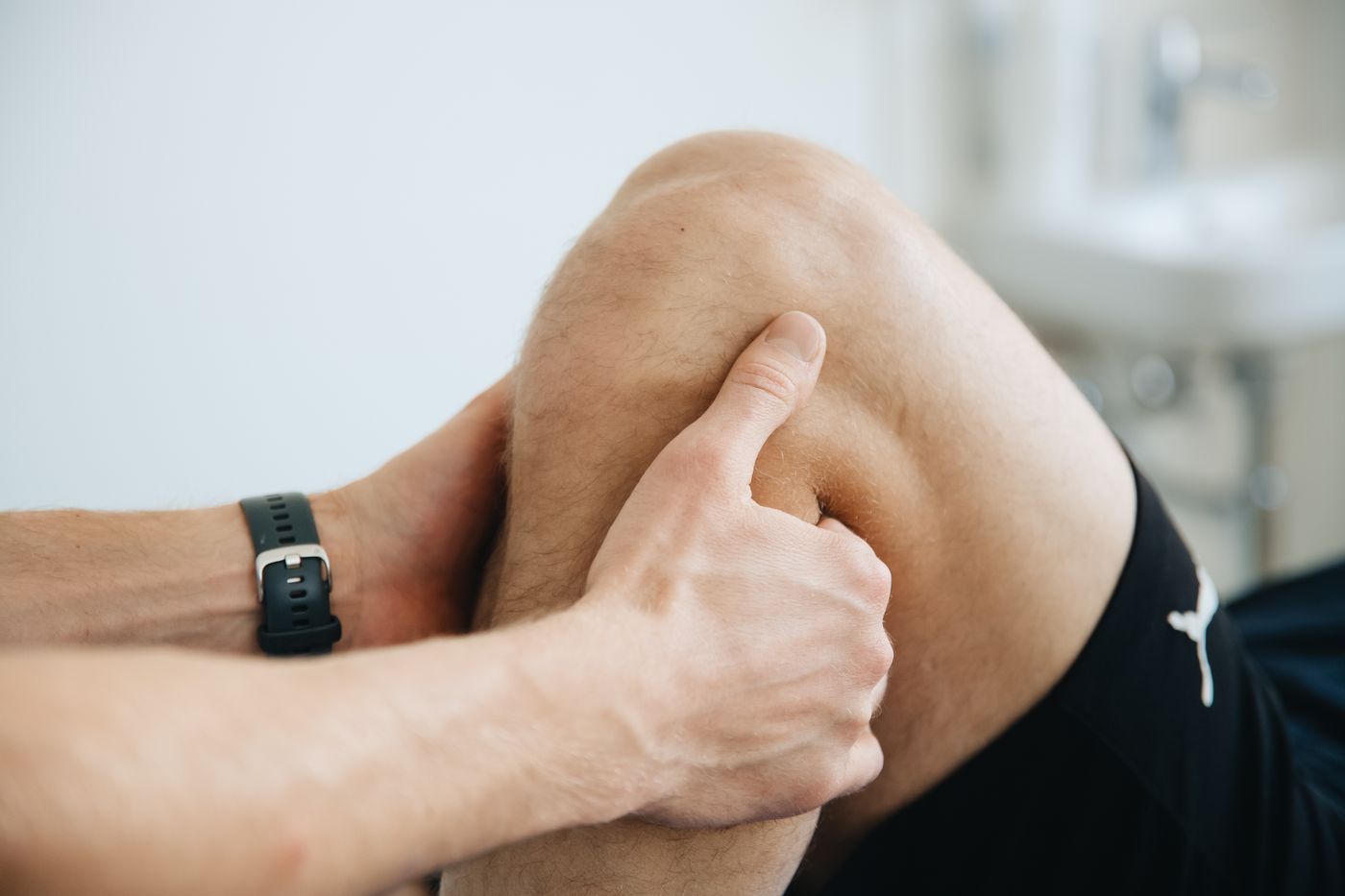 A practitioner applying pressure around a patient's knee