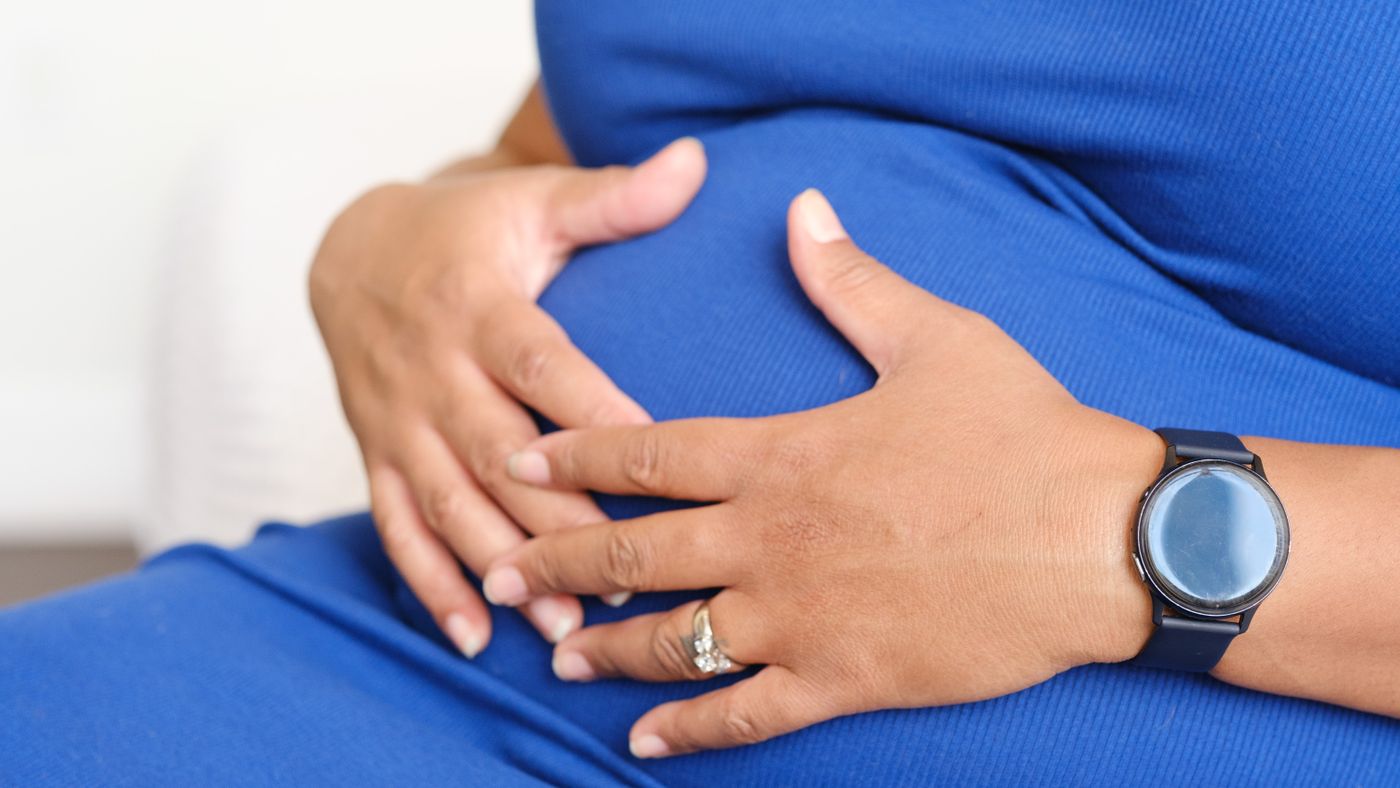 A pregnant person resting their hands on their bump