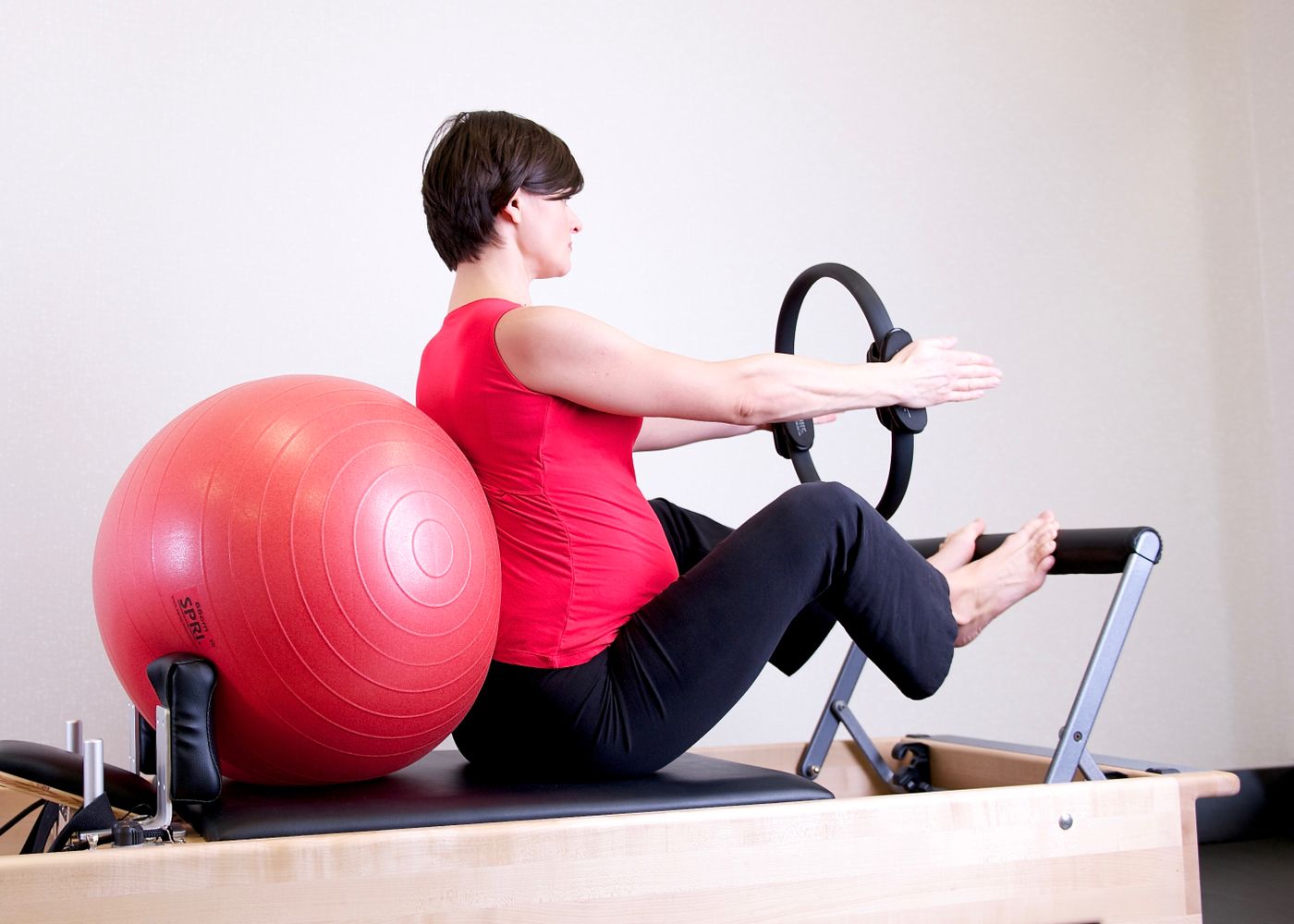 A pregnant person exercising with equipment