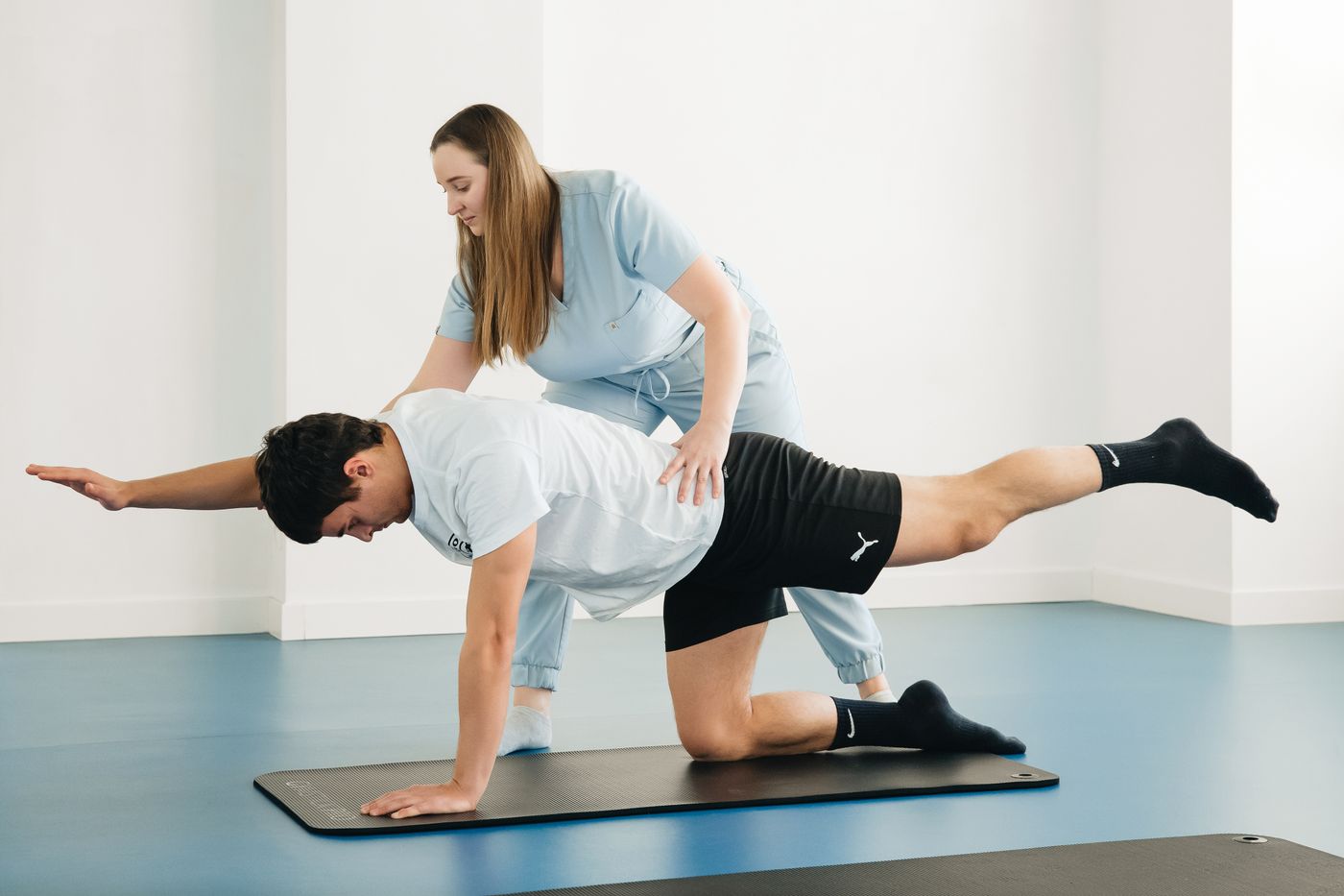 A practitioner coaching a patient through a floor exercise
